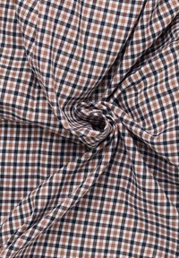 Tessuto di cotone a quadri nei colori marrone, nero e bianco. Caratterizzato da un motivo a griglia con dimensioni dei quadrati variabili, texture morbida e leggero cadere.