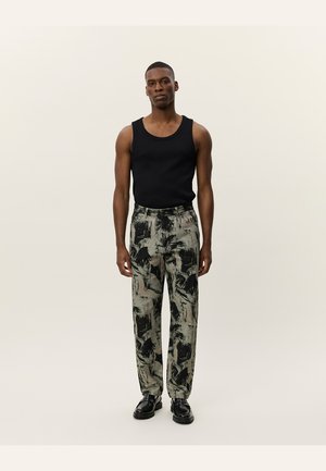 Black tank top, patterned grey and green trousers, tailored fit, and black shoes. The trousers feature abstract brushstroke designs.
