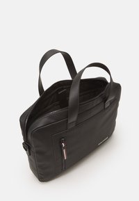 Borsa per laptop nera in materiale sintetico con due manici, chiusura superiore con zip e una tasca con zip frontale con un accento rosso e bianco. L'interno è foderato.