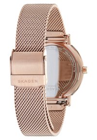 Roséguld klocka med en mesharmband. Har en cirkulär klockkropp och en enkel låsning. Baksidan är genomskinlig, vilket avslöjar intrikata mekaniska detaljer.