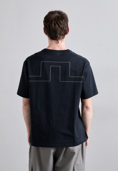 Schwarzes Baumwoll-T-Shirt mit einem geometrischen Umrissdesign in kontrastierendem weißen Faden auf dem Rücken. Kurze Ärmel und Rundhalsausschnitt.