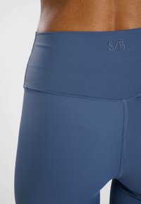 Leggings azul marino fabricados con una tela suave y elástica, con una cinturilla alta y costuras mínimas, y un logo sutil en la parte posterior.