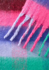 Daugiaspalvė vilnos šalikas su rožinėmis, violetinėmis ir žaliomis juostelėmis, tekstūruotomis kutais ir minkšta, pūkuota apdaila.