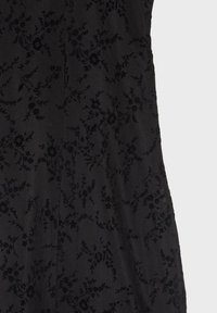 Tissu noir avec un motif jacquard floral subtil comportant de petites fleurs et des vignes sinueuses dans un tissage texturé.