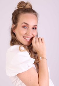 Gouden armband met drie kralen in pastelkleuren: lichtblauw, roze en wit. Het ontwerp heeft een delicate, gelaagde uitstraling.