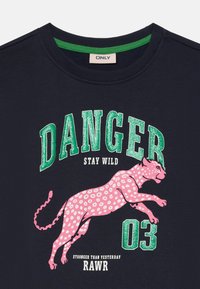 Ναυτικό μπλουζάκι με γυαλιστερό πράσινο κείμενο "DANGER 03" και γραφικό με ροζ λεοπάρδαλη με φράσεις "STAY WILD" και "STRONGER THAN YESTERDAY RAWR."