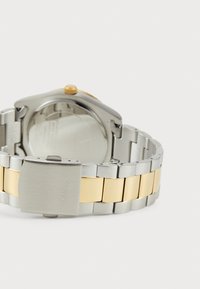 Stainless steel watch with a two-tone bracelet in silver and gold. Round case with a gold crown. Brushed metal clasp with engraved brand name.