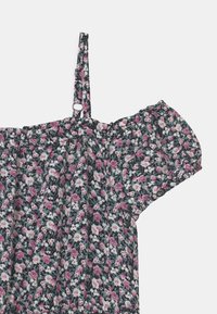 Haut floral sans épaules avec un fond bleu marine, orné de fleurs roses et blanches ; manches volantes et bretelles ajustables. Texture de tissu douce.