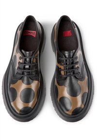 Chaussures en cuir noir avec de grands pois bruns, bout rond, semelle plate en caoutchouc et lacets noirs. Étiquettes "CAMPER" et "TWINS" visibles à l'intérieur.