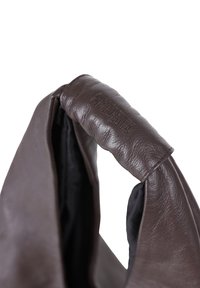 Sac en cuir marron avec une poignée rembourrée. L'intérieur est en tissu noir, présentant un logo subtil embossé sur la poignée.