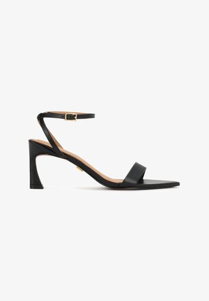 Black leather sandal with a minimal design, featuring a slim ankle strap with a gold buckle and a low, angled heel.