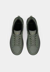 Green leather sneakers with a smooth texture, round toe, and perforated details. Features flat laces and gold logo on the tongue.
