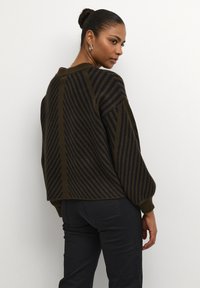 Pull en crochet de couleur vert foncé avec des rayures bleu marine, arborant une coupe ample, un col rond et des poignets côtelés. Le modèle fait face à l'arrière, montrant le design du dos.