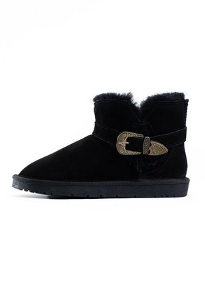 Black suede ankle boot with shearling cuff, featuring a decorative buckle and strap accent, and a flat rubber sole.