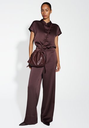 Ensemble en satin marron composé d'un haut à boutons à manches courtes et d'un pantalon à jambes larges. Comprend un sac à cordon assorti et des chaussures à bout pointu.