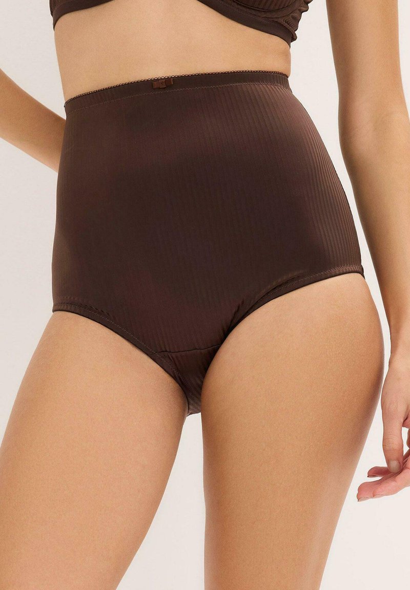 Slip con vita alta di colore marrone con texture a coste, abbinato a un top coordinato. Presenta una cintura elastica liscia e un design minimalista.
