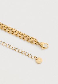 Βραχιόλι από χρυσό τόνο με κούμπωμα αστακού και ρυθμιζόμενη αλυσίδα που καταλήγει σε ένα μικρό στρογγυλό charm με χαραγμένο λογότυπο.