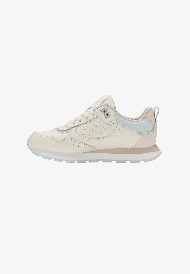 Zapatilla beige de perfil bajo con suela blanca, detalle en azul claro en el talón, collar acolchado y cierre de cordones, mostrada desde el lado externo.