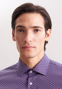 Camicia button-up viola con un motivo geometrico di piccoli cerchi concentrici in rosa e bianco. Tessuto morbido, design del colletto classico.