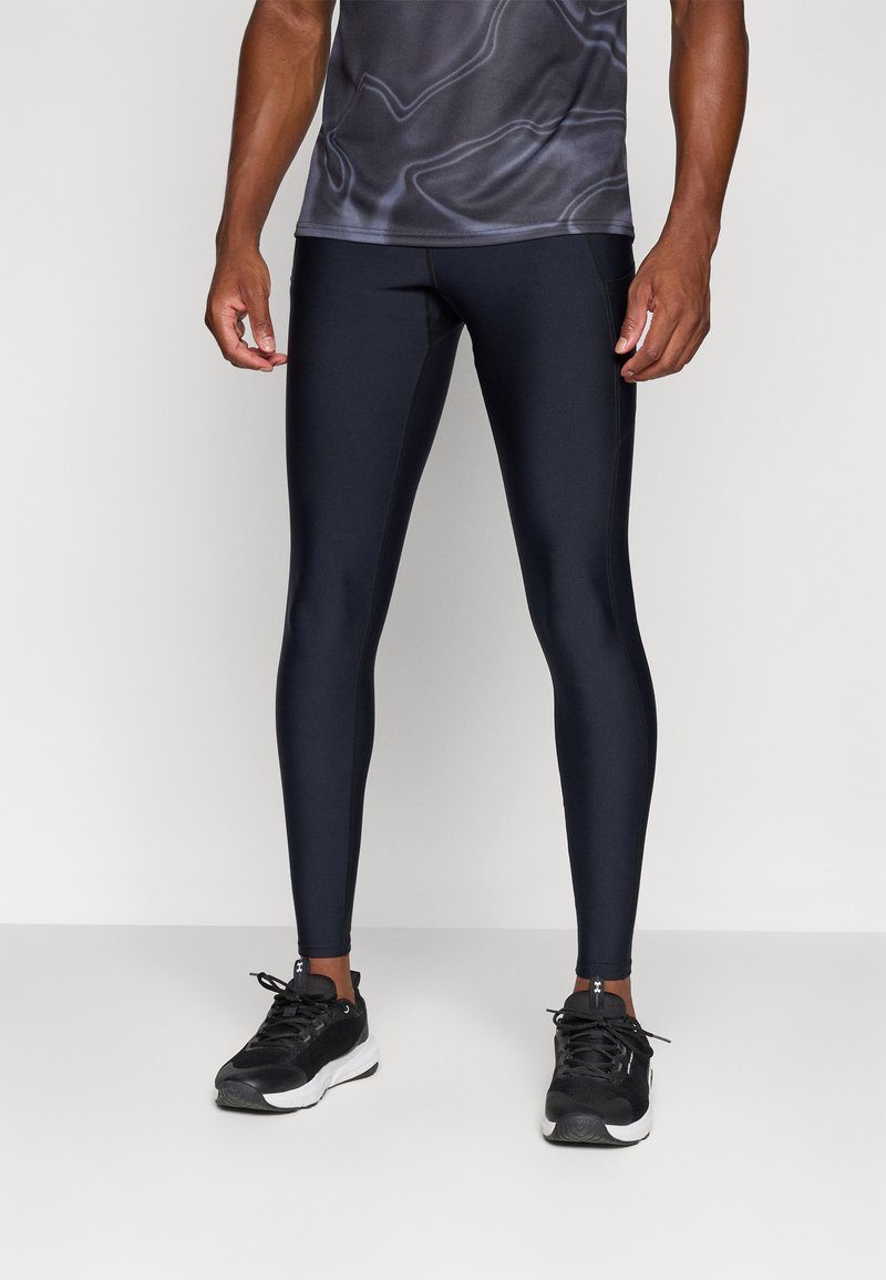 Marineblauwe sportleggings van een soepel, rekbaar materiaal, met een aansluitend ontwerp en zichtbare naden. Gecombineerd met zwarte loopschoenen.