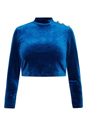 Modrý sametový zkrácený top s dlouhým rukávem a vysokým límcem, na jednom rameni jsou tři ozdobné knoflíky. Na látce jsou jemné tečky.