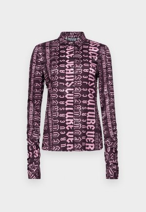 Pikendatud varrukatega pluus, millel on tume lilla kangas ja julge roosa graafiline tekst kogu ulatuses. Sisaldab kraega kaelaosa ja kokku volditud varrukaid.