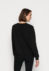 Felpa nera realizzata in un tessuto morbido. Dotata di maniche lunghe, collo rotondo e polsini e orlo a coste. Design semplice, senza motivi o dettagli.