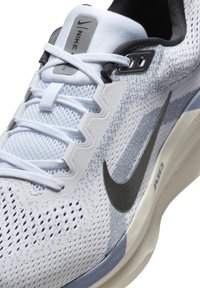 Nike trkačke tenisice u svijetloplavoj boji i bijelom pletenom materijalu, s crnim logotipom, teksturiranim dizajnom i sivim naglascima na jeziku i rupama za vezanje.