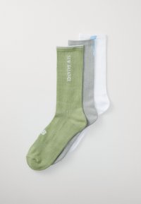 Tres pares de calcetines acanalados: verde, gris y blanco. Cada uno tiene un puño con acentos de color contrastante y la marca "New Balance" en blanco.
