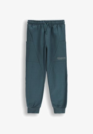 Morskie spodnie dresowe wykonane z miękkiego materiału z elastycznym pasem, ściągaczami przy mankietach oraz dużymi bocznymi kieszeniami; ozdobione napisem na udzie.