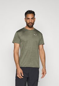 Olive roheline sportlik T-särk kergest kangast, ümmarguse kaelusega. Esipoolt kaunistab väike valge logo vasakul rinnal.