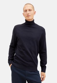 Granatowy sweter z golfem wykonany z miękkiej dzianiny z prążkowanymi mankietami i dołem, charakteryzujący się klasycznym krojem, który umożliwia wygodne warstwowanie.