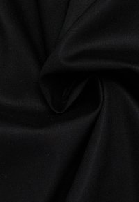 Tessuto nero con una texture liscia, caratterizzato da una tessitura semplice. Il materiale è stropicciato, mostrando morbide pieghe e una leggerissima lucentezza.