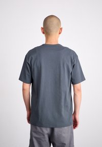 Grey cotton t-shirt with a standard crew neck and short sleeves, viewed from the back. Soft texture, relaxed fit, and no visible branding.
