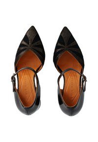 Chaussures en cuir noir avec un bout pointu, des découpes décoratives, une finition brillante et une bride réglable à la cheville. Présentent une doublure intérieure en tan.