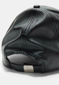 Schwarze Lederkappe mit einer strukturierten Oberfläche, sichtbaren Nähten und einem verstellbaren metallischen Riemen auf der Rückseite.