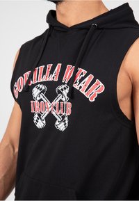 Zwarte mouwloze hoodie van katoen, met de opdruk "GORILLA WEAR IRON CLUB" in wit en rood, en een voorzak met kangoeroe-stijl.