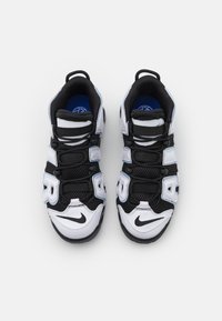 Fekete-fehér sportcipők hálós panelokkal, párnázott nyelvvel és tépőzáras pántokkal; kék talpbetéttel és hangsúlyos swoosh logóval rendelkeznek.