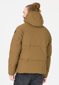 Brun polstret jakke med hætte, med et quiltet design og et sort accentlabel påærmet. Glat tekstur og afslappet pasform.