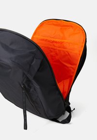Black backpack with an orange interior, featuring a zip closure, side zipper pocket, and multi-functional interior organization pockets.