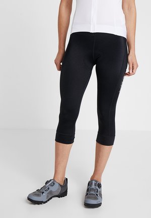 Leggings capri pretos com um design ajustado, feitos de material elástico, apresentando uma textura suave e comprimento cropped. Combinados com sapatilhas de desporto cinzas.