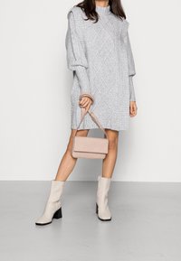 Ljusgrå stickad klänning med kabelmönster, matchad med en beige axelväska och krämfärgade ankelstövlar med klack.