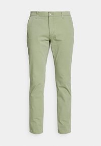 Chinos verde claro con un corte slim, presentan un cierre de botones, trabillas para cinturón y un diseño estándar de cinco bolsillos. Material de algodón suave.
