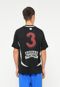 Juoda sportinė marškinė su raudonu skaičiumi "3" ir "ADIDAS RACING" logotipu. Turi trumpas rankoves ir kontrastingus pilkus akcentus. Lygus paviršius.
