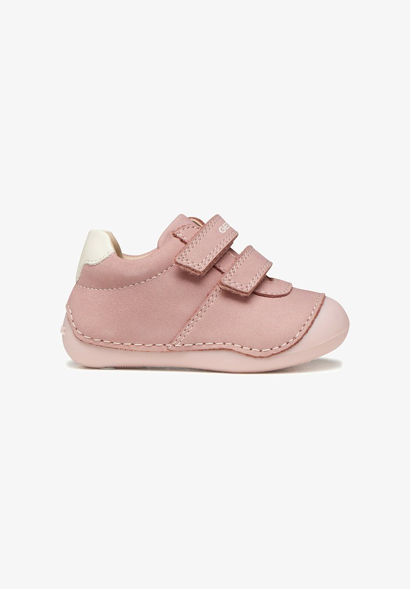 Zapato rosa para niño pequeño con dos tiras de Velcro, parche blanco en el talón, suela blanda y costuras visibles sobre un fondo blanco.