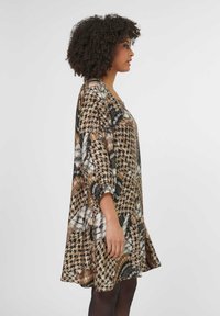 Braun gemustertes knielanges Kleid mit 3/4-Ärmeln, das ein Hahnentrittmuster und florale Akzente in Schwarz, Weiß und Orangetönen aufweist.