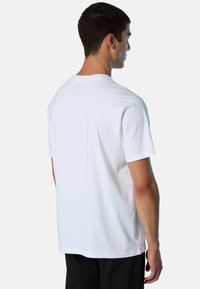T-shirt bianca in cotone con vestibilità rilassata, colletto a girocollo e maniche corte. Presenta un orlo dritto e un'etichetta logo discreta sul retro.