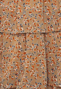 Tissu beige avec volants superposés, décoré d'un petit motif floral orange et bleu foncé et de tiges gris clair.