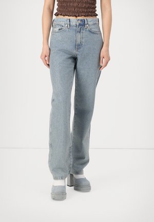Light blue denim jeans with a relaxed fit, featuring five-pocket styling, belt loops, and subtle fading. Worn with grey platform shoes.