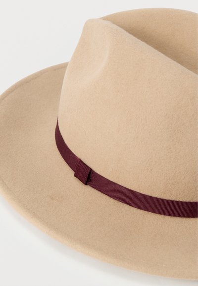 Μπεζ τσόχινο καπέλο με φαρδύ γείσο και κορδέλα από σατέν βουργουνδί στο κάτω μέρος. Λείο ύφασμα και καθαρές γραμμές σε κλασικό σχέδιο.